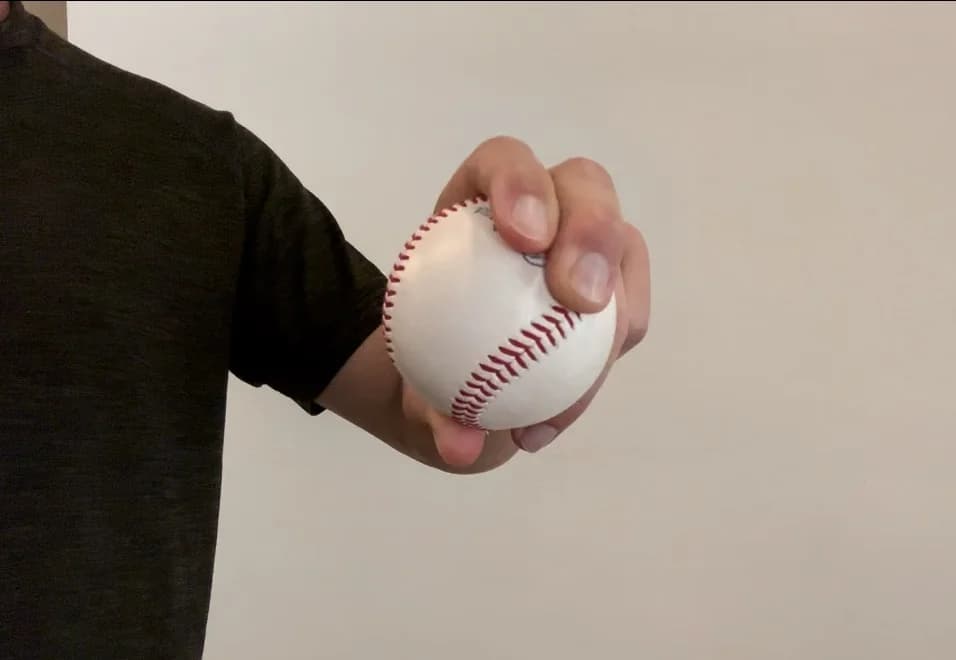 A pitcher holding a baseball in a pitch grip